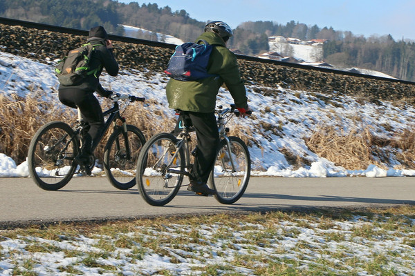 2 Radfahrer auf einer kleinen Straße, neben Bahngleisen